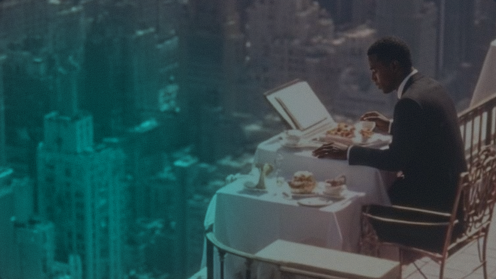 A man in a suit sitting at a table on a high balcony overlooking a vast cityscape with a teal-tinted filter, representing strategic financial perspective and global economic infrastructure