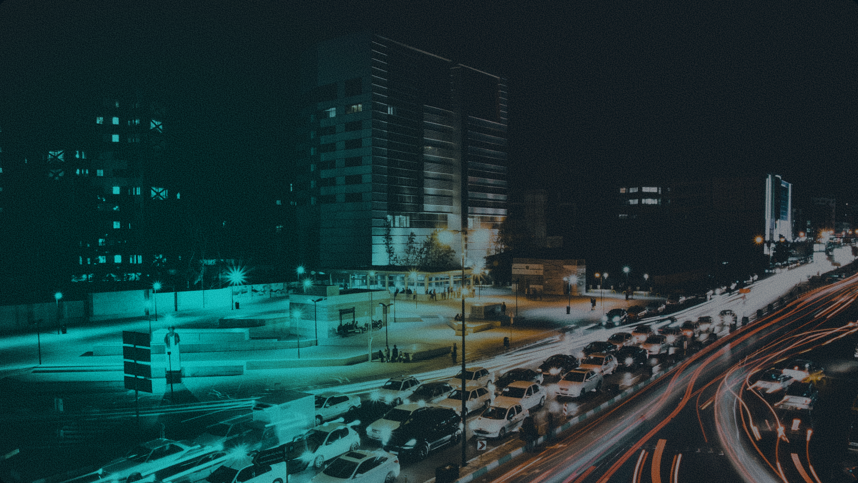 An aerial night view of city traffic lights and modern office buildings under a teal-tinted lens, symbolizing urban liquidity and real-time cross-border financial movement