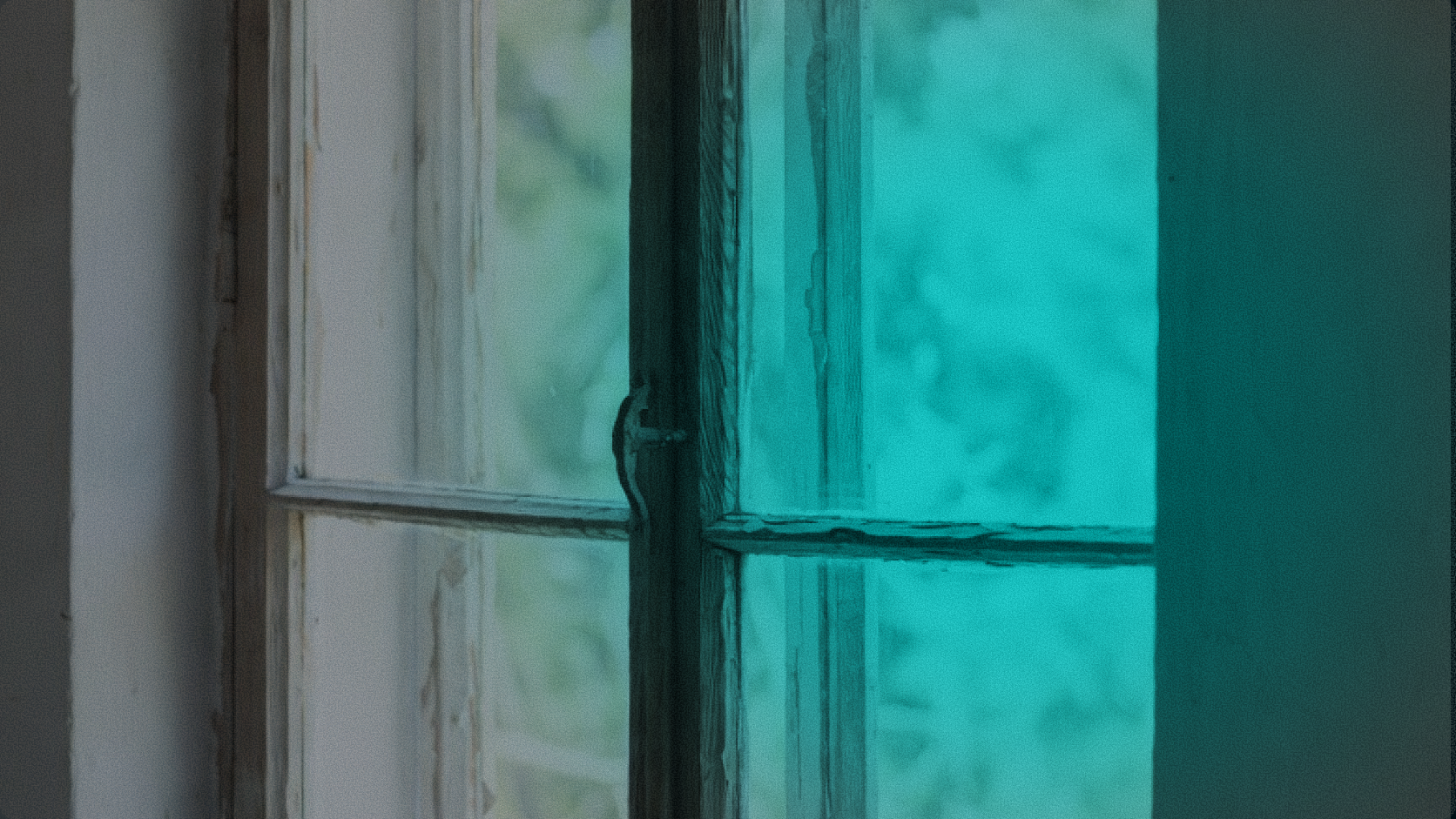 Close-up of a vintage window with teal-tinted glass panes, illustrating the concept of payment settlement windows and processing cut-offs in cross-border banking